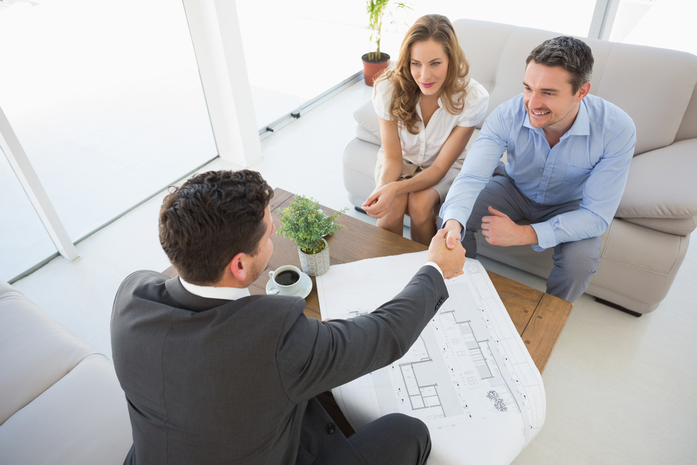 High angle view of a smiling young couple in meeting with a financial adviser at home